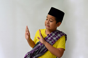 A portrait of an Asian Muslim boy with an expression of rejecting something