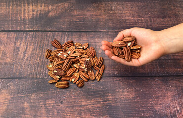 Unrecognizable woman holding a bunch of walnut sand some more over the wooden table.