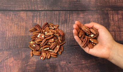 Unrecognizable woman holding a bunch of walnut sand some more over the wooden table.