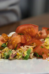adding chopped red tomatoes on top of an omelet