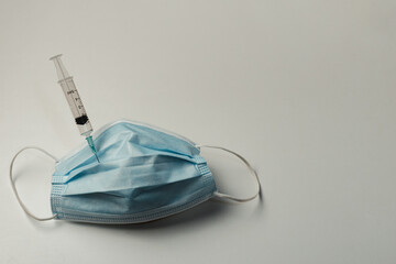 syringe and medical mask on a white background. Vaccination concept for coronavirus