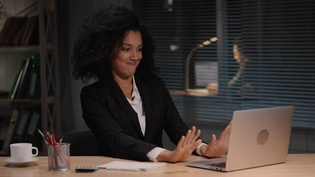 Portrait of African American woman typing on laptop, sends an email to client and is happy with result. Businesswoman sitting at table in interior of office. Slow motion ready, 4K at 59.94fps.
