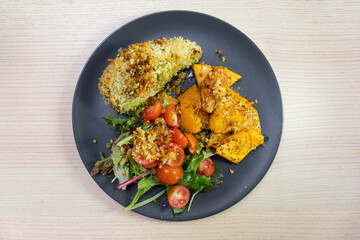 A plate of crumbed chicken, baked pumpkin, and salad.