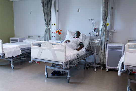 African american male patient lying on hospital bed wearing oxygen mask ventilator