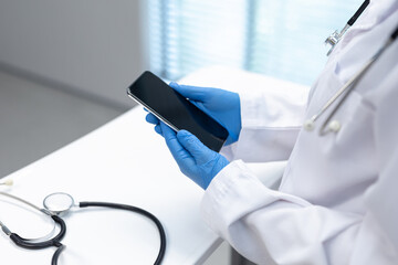 Midsection of doctor wearing latex gloves using smartphone with copy space on screen