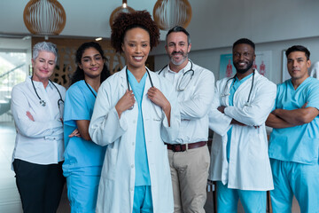 Portrait of group of diverse male and female doctors standing in hospital corridor smiling to camera