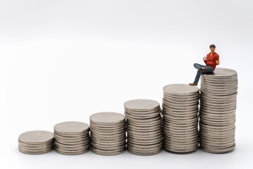 Business, Money Investment and Team Concept. Businessman miniature figure people figure with cup of hot coffee sitting on top of stack of silver coins on white background.