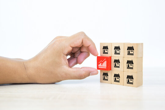 Franchise, Hand choose graph icon on cube wooden toy blocks stacked with franchise business store icon for growth and financial marketing planning and bank loan for branch expansion franchisee.