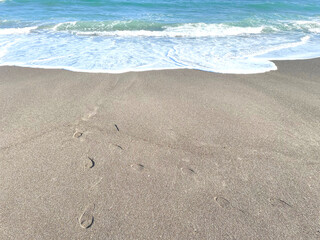 Fototapeta na wymiar 砂浜と足跡と打ち寄せる波