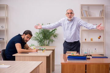 Old male teacher and young male student in the classroom