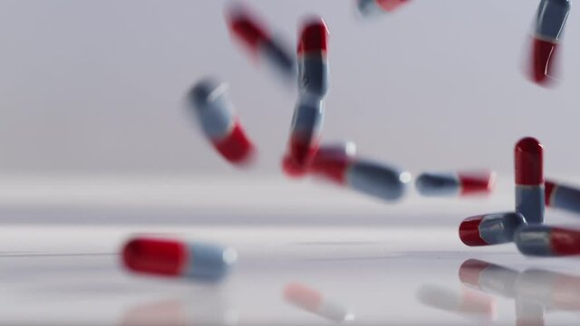 Close up shot of red and blue pills falling and bouncing on a surface