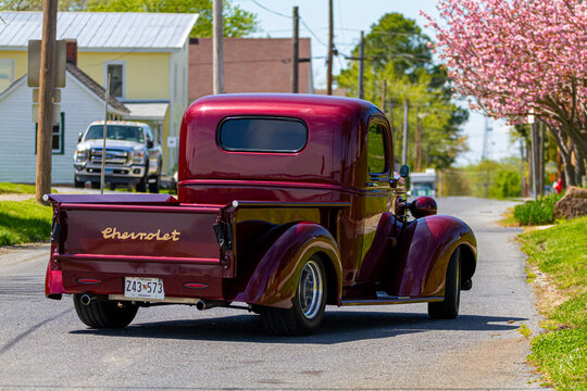 Vienna, MD, USA 04-16-2021: A vintage red shiny Chevrolet Master series pickup truck (built between 1933-1940) is on the road at a residential neighborhood. Well maintained vehicle has historic tag