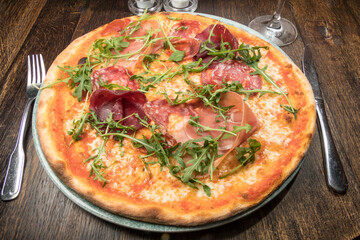 A pizza with parma ham and ruccola.