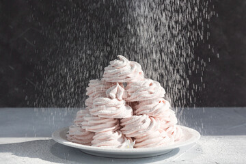 Sprinkling marshmallow pile with icing sugar. Tasty zephyr.