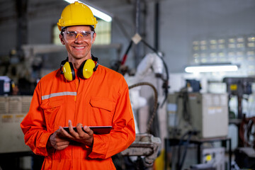 Portrait of factory worker man with protection suit stand with confidence smiling in front of industrial robotic machine in workplace area. Employee support system help in industrial business concept.