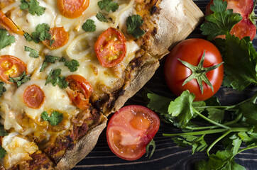 Pinsa with a decor in the form of tomatoes and greens on a colored background close-up. Pinsa home cooking.