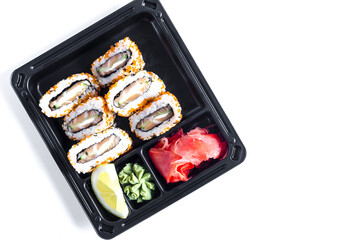 fresh fish cucumber and cheese rolls decorated with sesame seeds. Wasabi and ginger rolls in a dark plastic bowl top view. Red Rolls food delivery concept