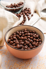 Bowl with chocolate corn balls on light background