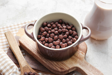 Bowl with chocolate corn balls on light background