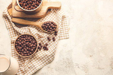 Bowls and spoon with chocolate corn balls on light background