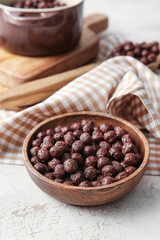 Bowl with chocolate corn balls on light background