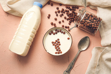 Bowl with chocolate corn balls and milk on color background