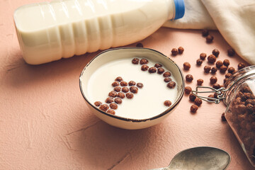 Bowl with chocolate corn balls and milk on color background