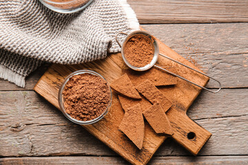 Bowl and sieve with cocoa powder on wooden background