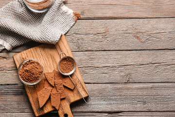 Bowl and sieve with cocoa powder on wooden background