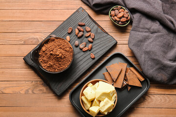 Bowls with cocoa powder, chocolate and beans on wooden background