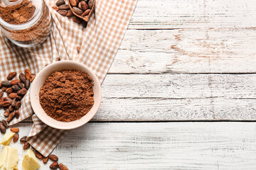 Bowl with cocoa powder on light wooden background