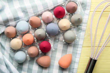 Naklejka premium Creative composition with makeup sponges and whisk on color wooden background