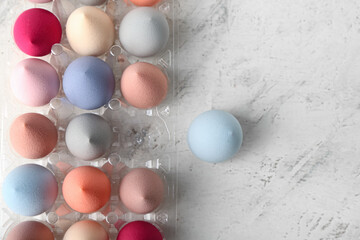 Plastic eggs holder with makeup sponges on light background, closeup