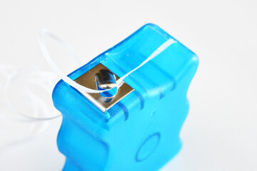 A close up image of a blue dental floss container on a white background. 