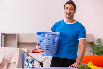 Young man husband doing ironing at home