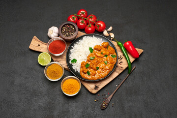 Plate of Traditional Chicken Curry, rice and spices on dark concrete background