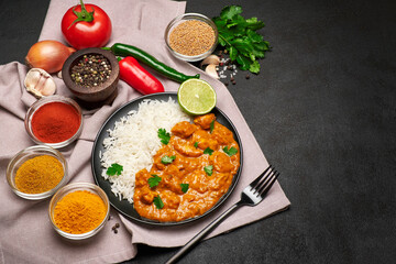 Plate of Traditional Chicken Curry, rice and spices on dark concrete background