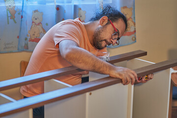 Man struggles to assemble wooden furniture at home. Carpentry
