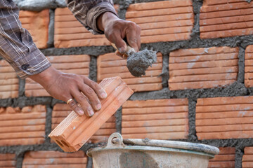 Red bricks and mason are building bricks to build the walls of the building. Working requires professional skills. A balanced mix of mortar and leveled bricks.