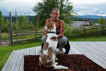 A woman is looking at a dog which's on a red carpet with green backgrounds 