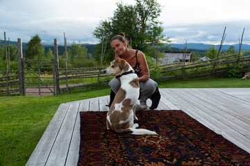 A woman is looking at a dog which's on a red carpet with green backgrounds 