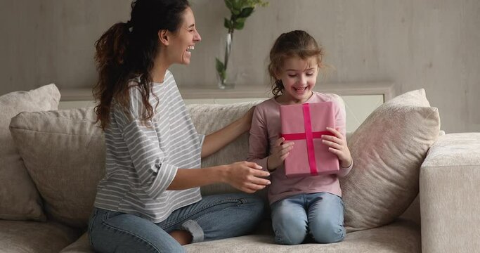 Mom makes gift for little daughter gives box congratulates birthday. Preschool girl cover eyes with hands anticipate mommy surprise, receiving pink package feel happy. Life events celebration concept