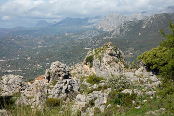 Mountains and trees in a green landscape with some clouds and blue sky
