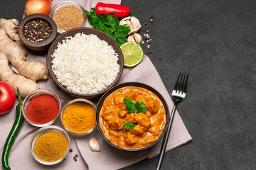 Plate of Traditional Chicken Curry, rice and spices on dark concrete background