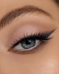 Obraz premium Beautiful macro shot of female eye make-up in smoky eyes style and arrow. Blue eye. Creative make-up. Perfect shape make-up and long lashes. Cosmetics. Beautiful eyes make-up. Close-up
