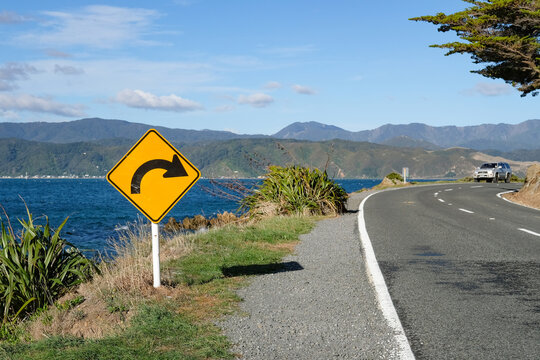 Sign warning of a upcoming bend on an ocean road