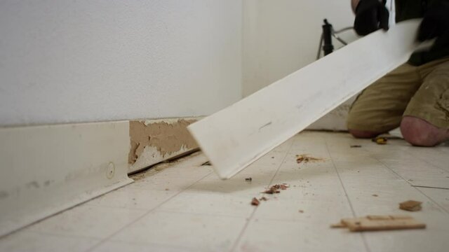 Man removing rubber base from wall during a bathroom remodel