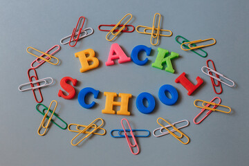 Back to school. The words are laid out in letters from a plastic magnetic alphabet among colored paper clips.