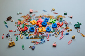Fototapeta na wymiar Back to school. The words are laid out in letters from a plastic magnetic alphabet among colored paper clips.