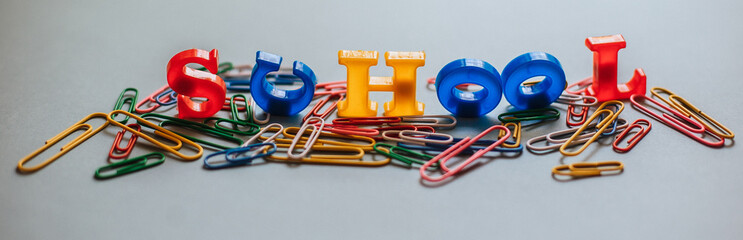 Back to school. The words are laid out in letters from a plastic magnetic alphabet among colored paper clips.